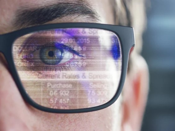 a person wearing glasses with a reflection of a chart