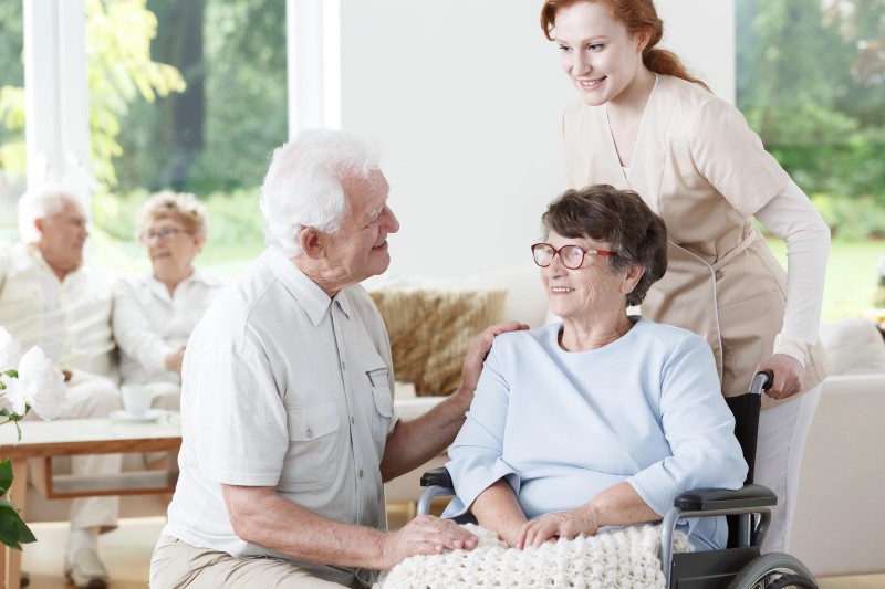 a woman helping an old man in a wheelchair